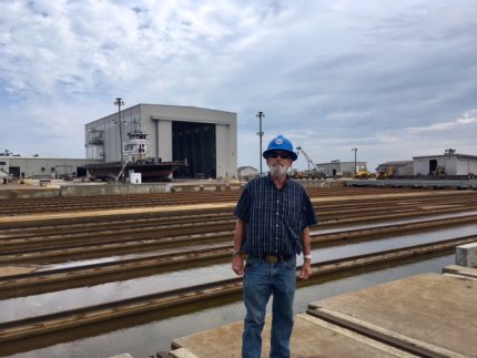 The author poses in his hard hat. Paint building in background.